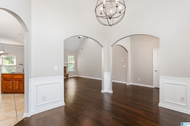 spare room with a notable chandelier, dark wood-type flooring, and plenty of natural light