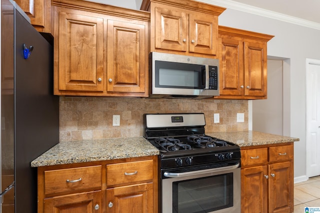 kitchen featuring tasteful backsplash, stainless steel appliances, light tile patterned floors, crown molding, and light stone countertops