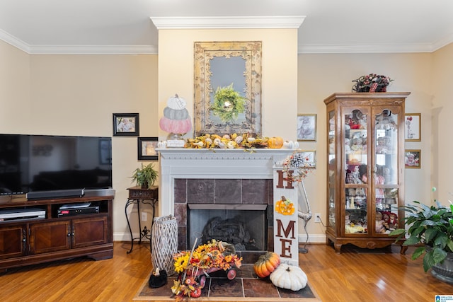 living room featuring light wood-type flooring, crown molding, and a fireplace