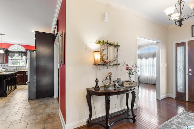 entryway featuring crown molding, sink, dark wood-type flooring, and a chandelier