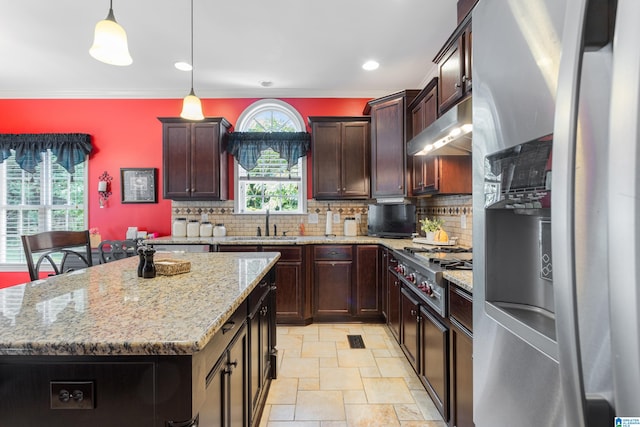 kitchen featuring appliances with stainless steel finishes, hanging light fixtures, ventilation hood, a center island, and sink