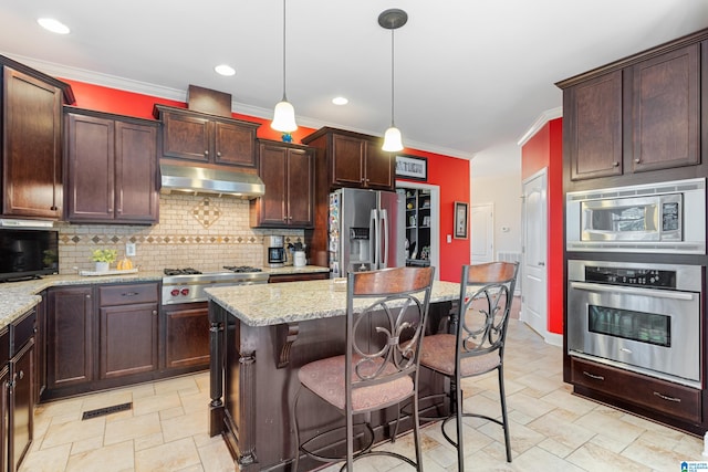 kitchen featuring light stone countertops, stainless steel appliances, hanging light fixtures, and a kitchen island