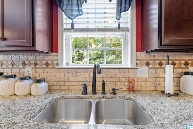 kitchen featuring light stone counters, tasteful backsplash, and sink