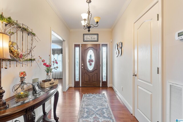 foyer featuring an inviting chandelier, hardwood / wood-style flooring, and ornamental molding