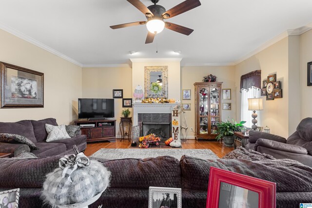 living room with crown molding, a fireplace, ceiling fan, and light hardwood / wood-style flooring