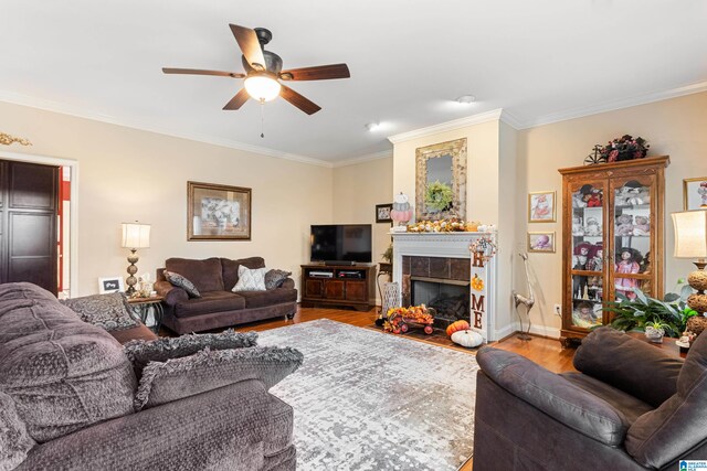 living room with ceiling fan, light hardwood / wood-style flooring, a tiled fireplace, and ornamental molding