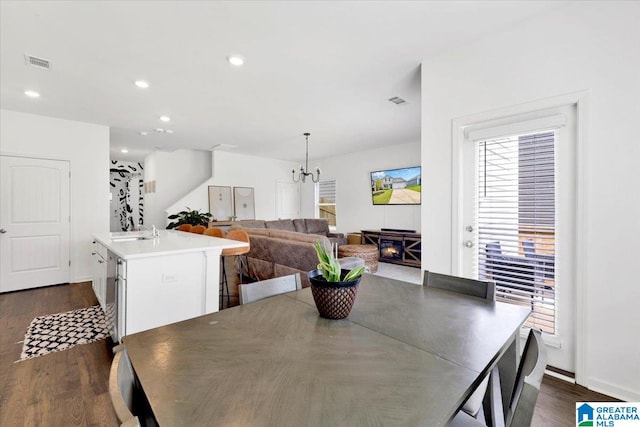 dining space with a chandelier, sink, a fireplace, and dark hardwood / wood-style flooring