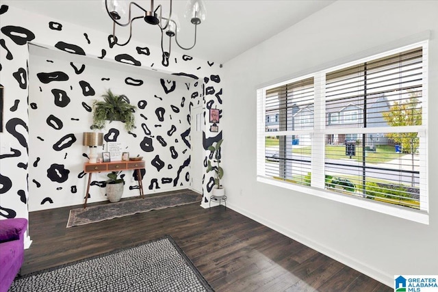 interior space featuring an inviting chandelier, a wealth of natural light, and dark hardwood / wood-style flooring