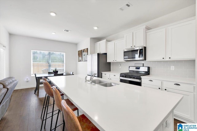 kitchen featuring appliances with stainless steel finishes, a kitchen island with sink, sink, and white cabinets