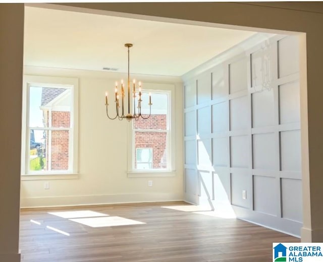 unfurnished dining area featuring an inviting chandelier and hardwood / wood-style flooring