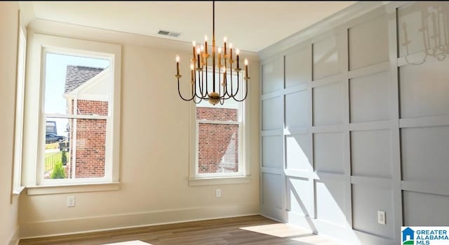 unfurnished dining area featuring a chandelier and dark hardwood / wood-style floors