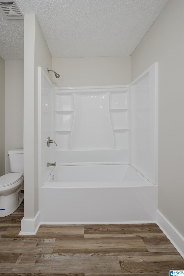 bathroom featuring hardwood / wood-style flooring, toilet, a textured ceiling, and shower / bathtub combination