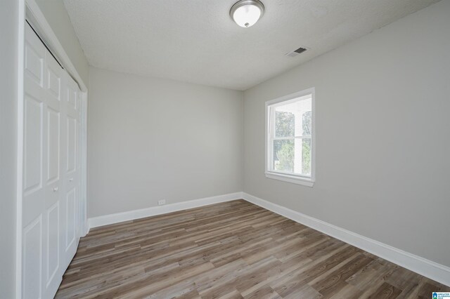 unfurnished room featuring wood-type flooring and a textured ceiling