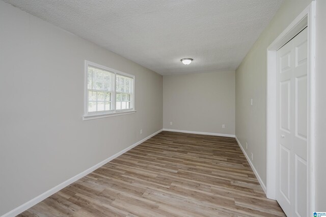 bonus room with a textured ceiling, lofted ceiling, and light hardwood / wood-style flooring