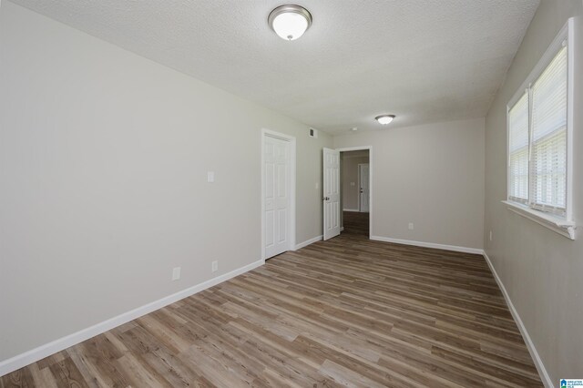 bonus room featuring a textured ceiling, wood-type flooring, and lofted ceiling