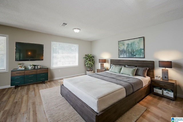 bedroom with light hardwood / wood-style floors and a textured ceiling