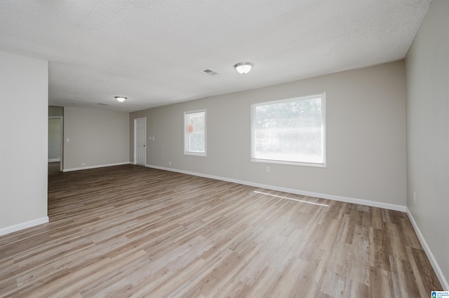 spare room featuring light wood-type flooring and a textured ceiling