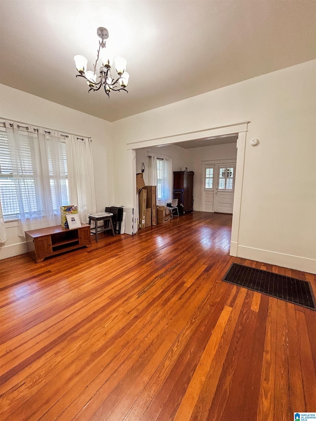 unfurnished living room featuring hardwood / wood-style floors, a chandelier, and plenty of natural light