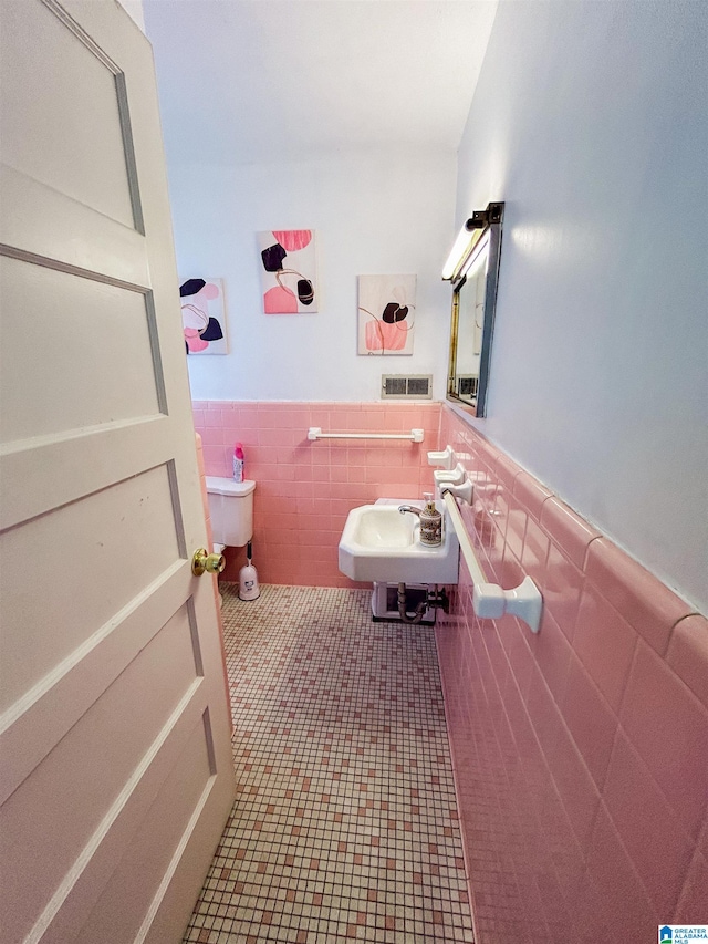 bathroom with toilet, tile walls, tile patterned flooring, and sink