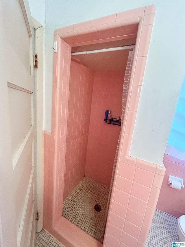 bathroom with toilet, tile walls, a tile shower, and tile patterned floors