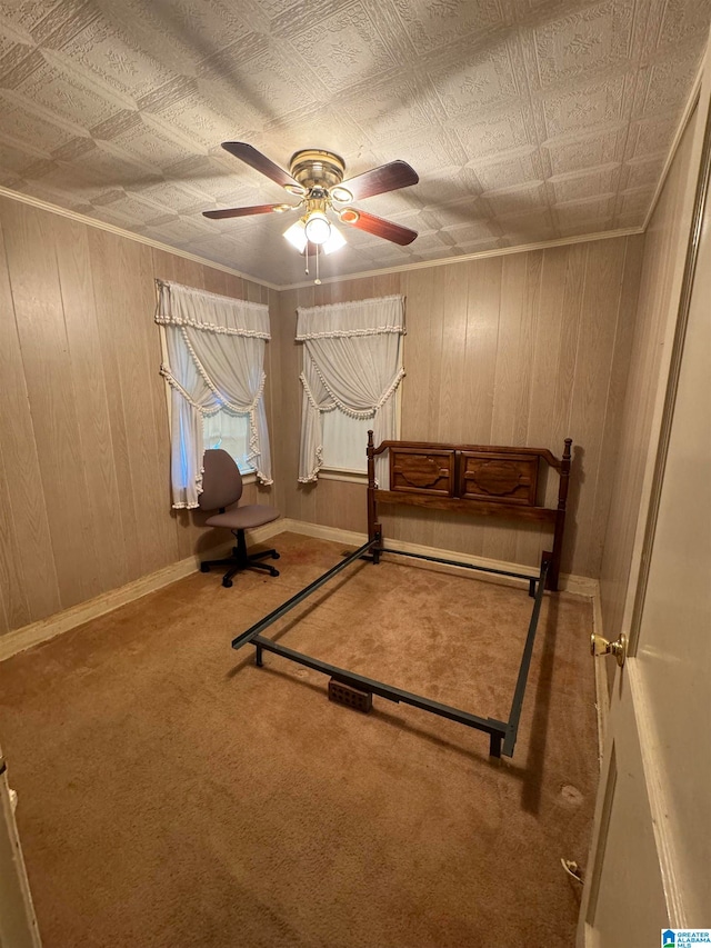 unfurnished bedroom featuring carpet flooring, wooden walls, and ceiling fan