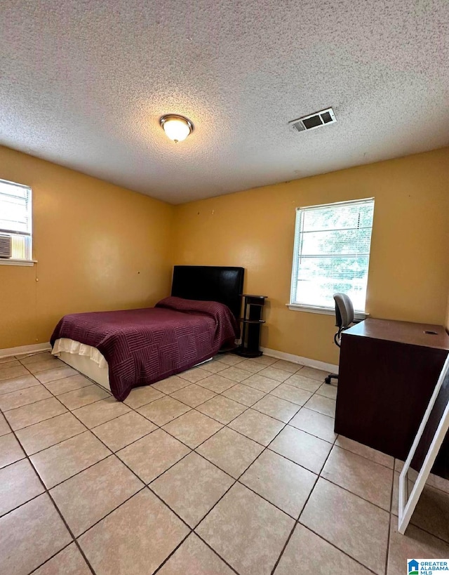 bedroom with multiple windows, a textured ceiling, and light tile patterned floors