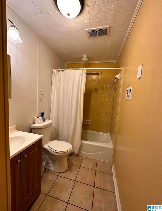 full bathroom with tile patterned flooring, a textured ceiling, shower / bath combo with shower curtain, vanity, and toilet