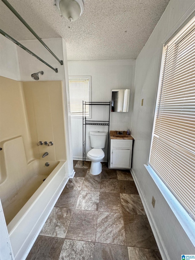 full bathroom with tub / shower combination, plenty of natural light, vanity, and toilet