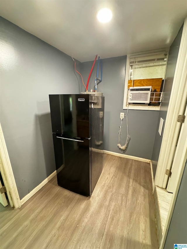 kitchen featuring cooling unit, light wood-type flooring, and black refrigerator