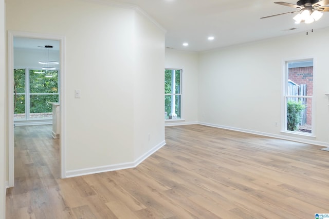 spare room featuring light wood-type flooring, plenty of natural light, crown molding, and ceiling fan