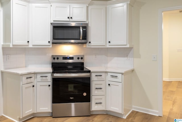 kitchen featuring appliances with stainless steel finishes, backsplash, light stone counters, white cabinets, and light hardwood / wood-style floors