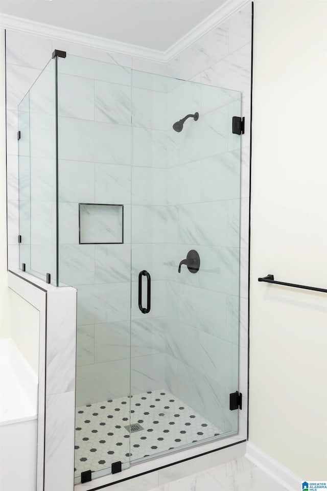 bathroom featuring ornamental molding and a shower with shower door