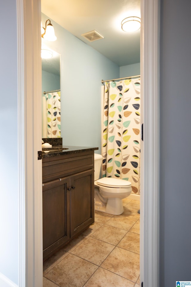 bathroom featuring curtained shower, vanity, toilet, and tile patterned floors