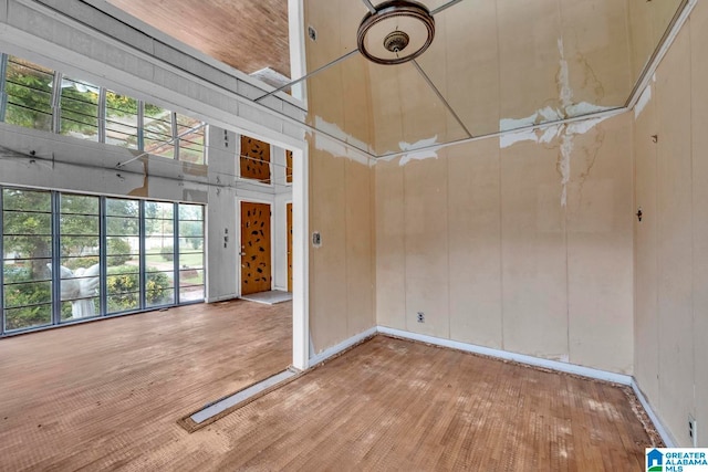 spare room with wood walls, a towering ceiling, and light hardwood / wood-style floors