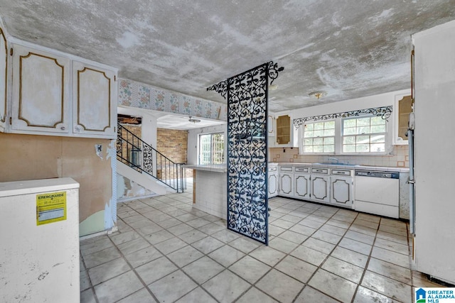 kitchen with light tile patterned flooring, sink, white dishwasher, and a wealth of natural light