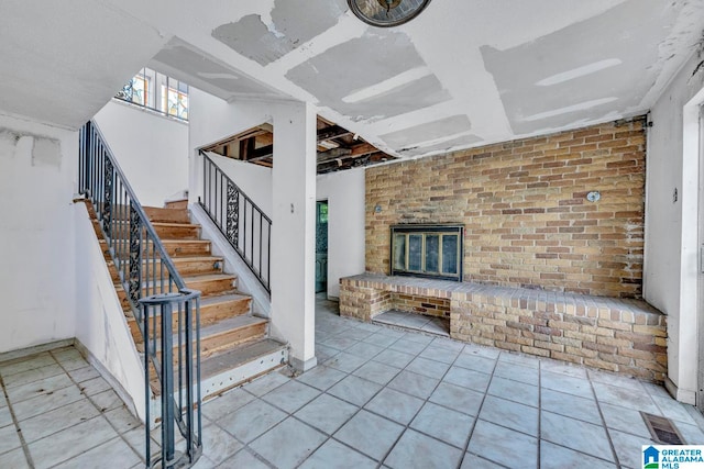 stairway with brick wall, a fireplace, and tile patterned floors