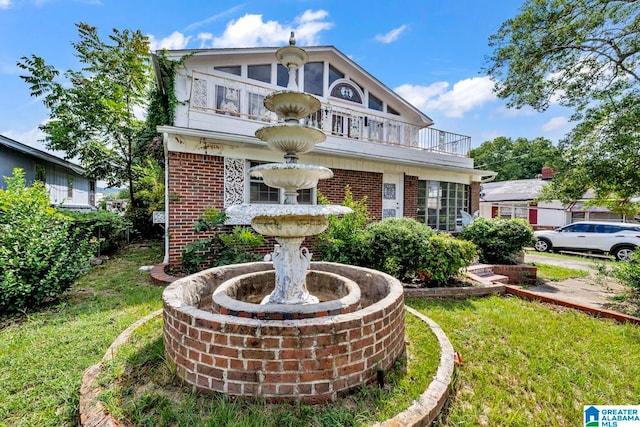 view of front of property featuring a balcony and a front lawn