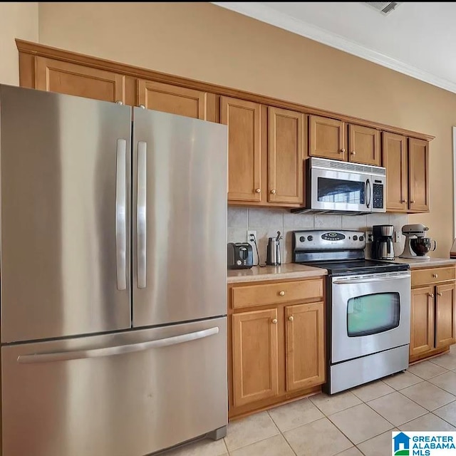 kitchen with crown molding, light tile patterned floors, stainless steel appliances, and tasteful backsplash