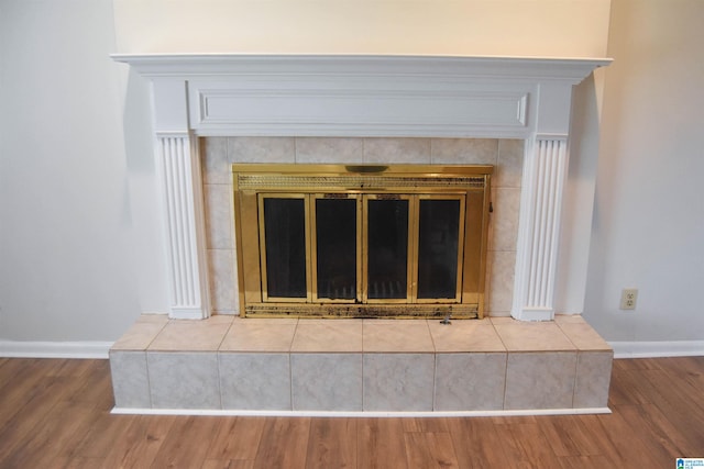 details with a tiled fireplace and hardwood / wood-style floors