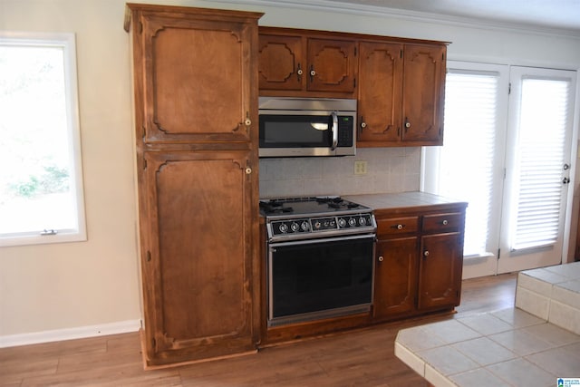 kitchen with hardwood / wood-style flooring, tile counters, range, and a wealth of natural light