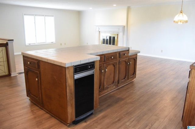 kitchen featuring decorative light fixtures, dark wood-type flooring, tile counters, and a center island