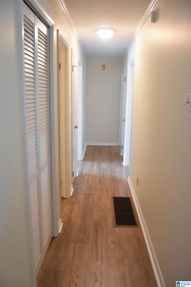 hall with light hardwood / wood-style flooring and crown molding