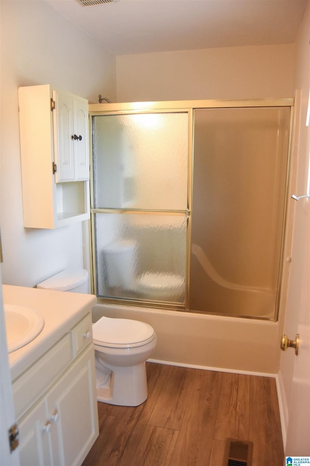 full bathroom with bath / shower combo with glass door, vanity, toilet, and hardwood / wood-style flooring