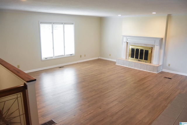 unfurnished living room with crown molding, a fireplace, and hardwood / wood-style flooring