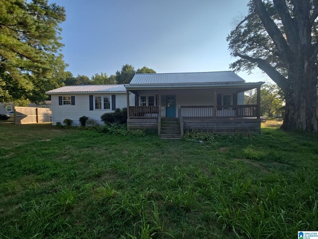 view of front of property featuring a front lawn, metal roof, covered porch, and fence