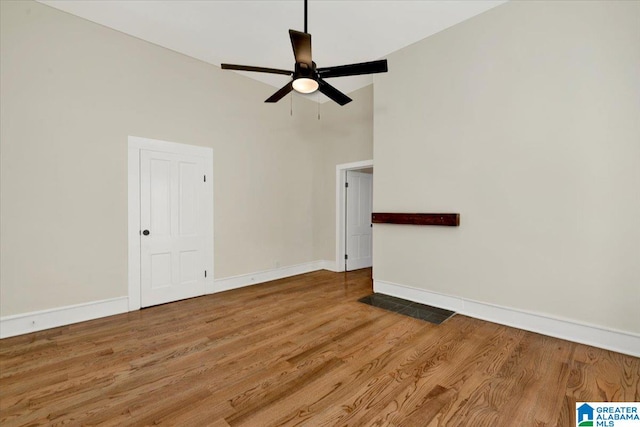 spare room with ceiling fan, hardwood / wood-style floors, and a high ceiling