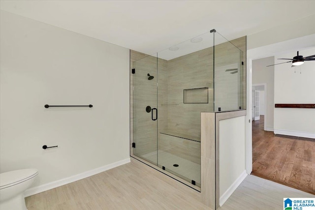 bathroom featuring toilet, a shower with door, hardwood / wood-style floors, and ceiling fan