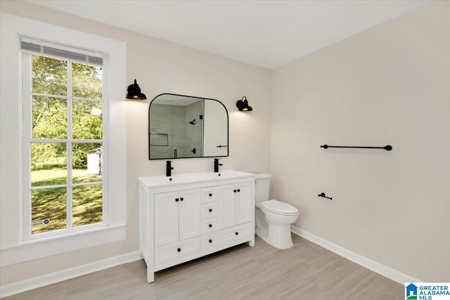 bathroom with hardwood / wood-style floors, walk in shower, vanity, and toilet