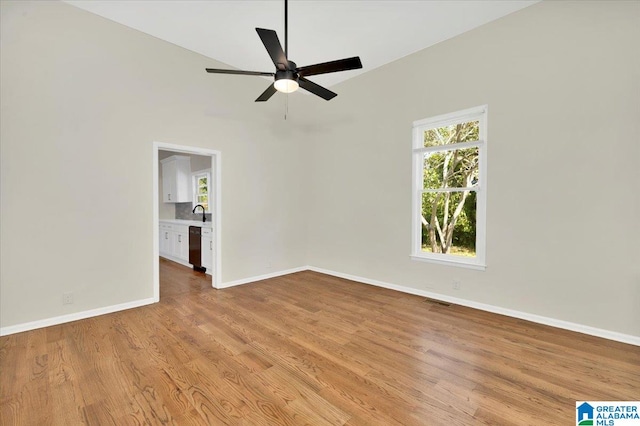 empty room with light wood-type flooring, ceiling fan, and sink