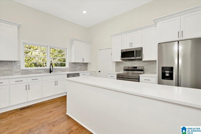 kitchen with light hardwood / wood-style flooring, appliances with stainless steel finishes, sink, and white cabinetry